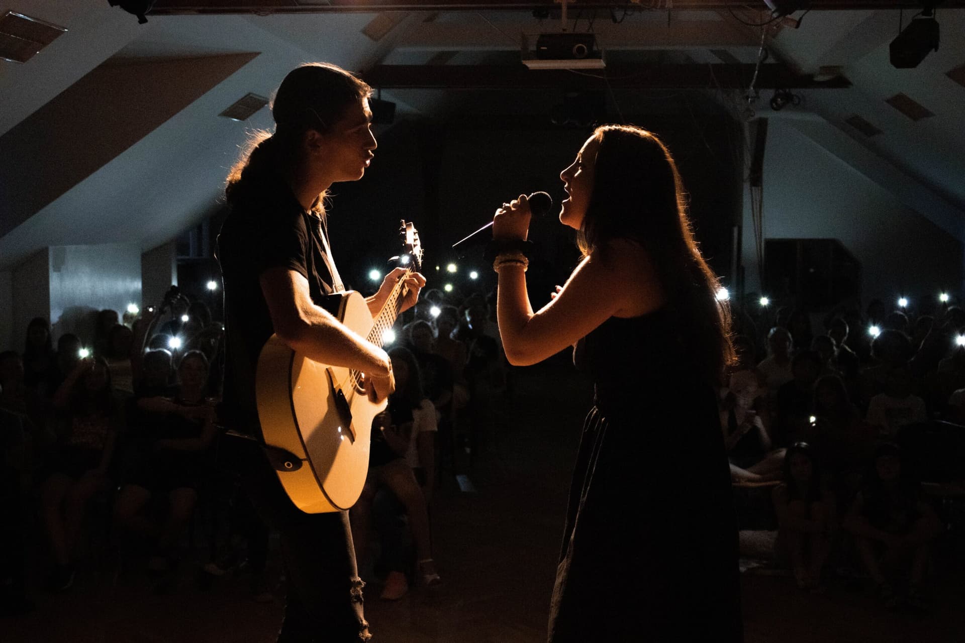 Pěvecké duo s kytarou při večerním vystoupení před publikem